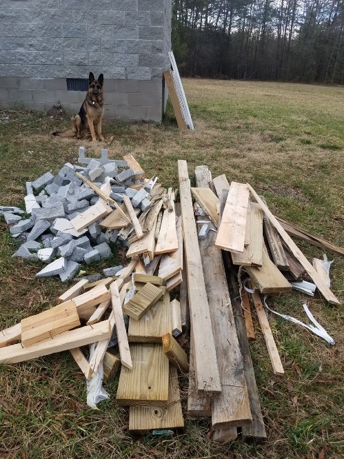 A pile of scrap wood and building materials outside on the grass