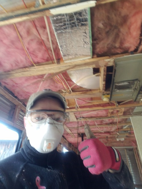 A woman with a face mask and safety goggles gives a thumbs up