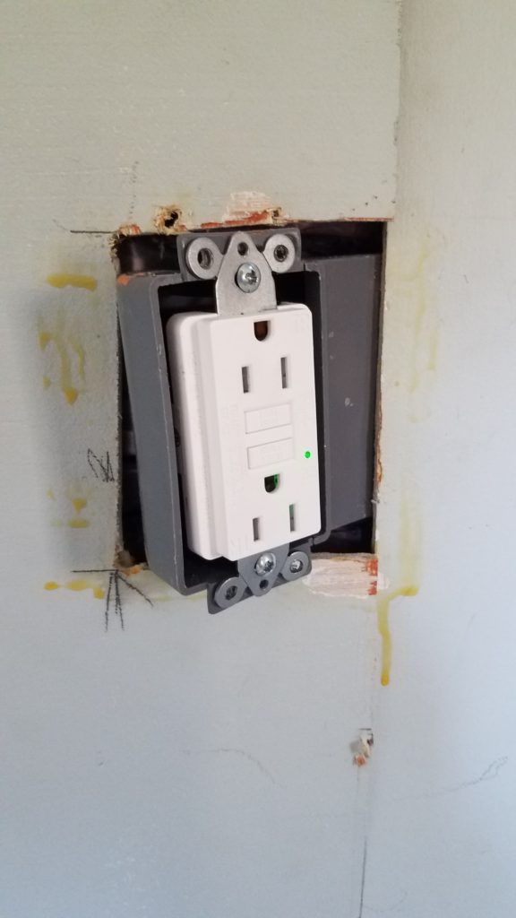 A GCFI receptacle being installed in a special wall box built for narrow spaces