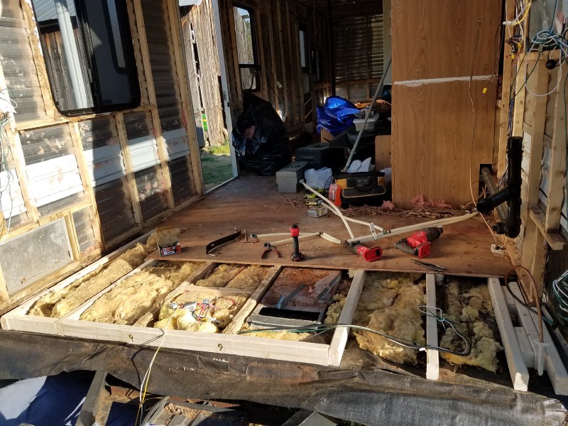 The floor of the travel trailer cut open and showing the joists and insulation, as well as wires.