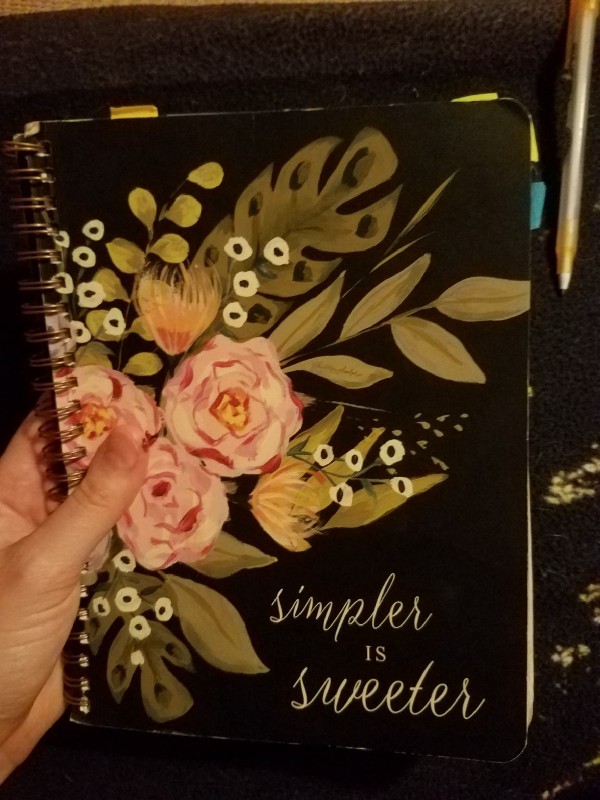 The cover of my notebook with a floral design and the words Simpler is Sweeter