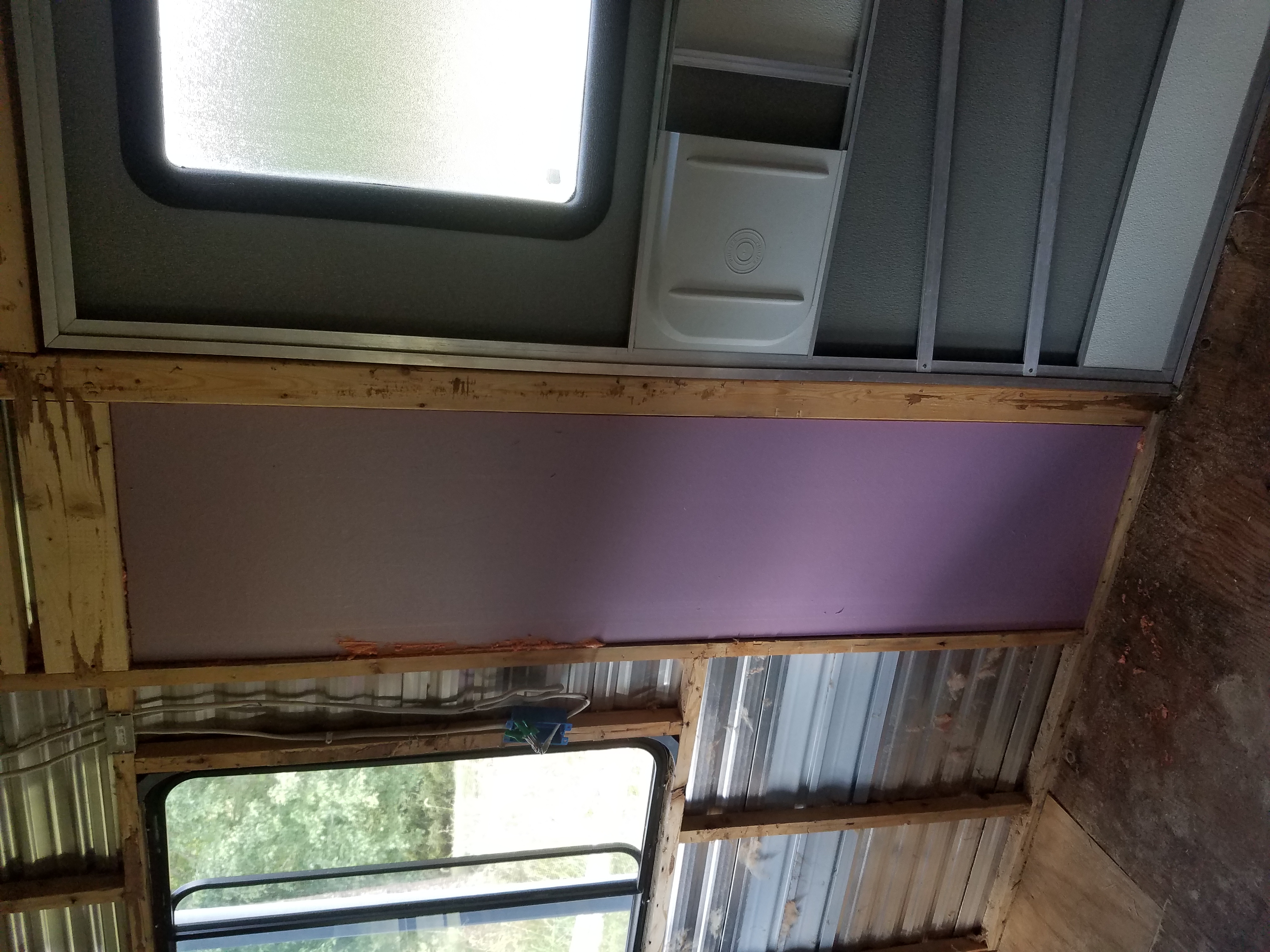 The inside of the travel trailer with the framing exposed and a square of purple foam board insulation in place