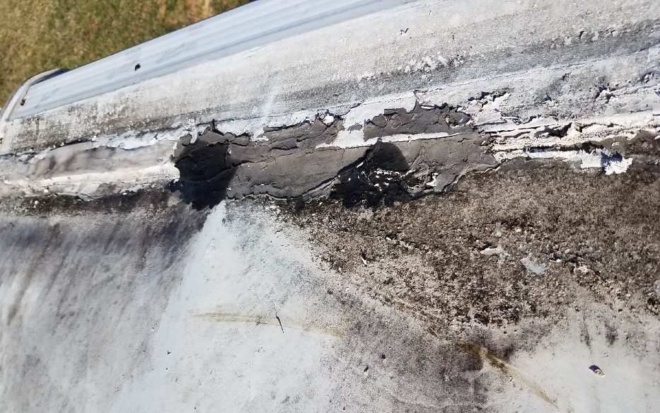 Travel trailer roof stained by rainwater pooling on cracked caulking.