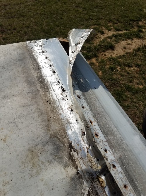 The travel trailer aluminum siding folds over the roof at the front of the trailer and is screwed into place.