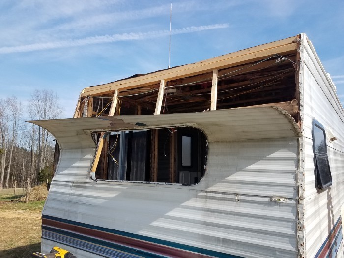 Removing the aluminum siding on the front of the travel trailer to reveal the wooden frame.