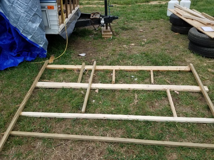 Lumber laying on the ground in the design of the frame.