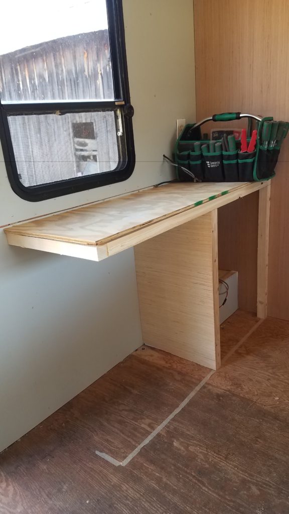 A partially completed desk and cabinet inside of the trailer